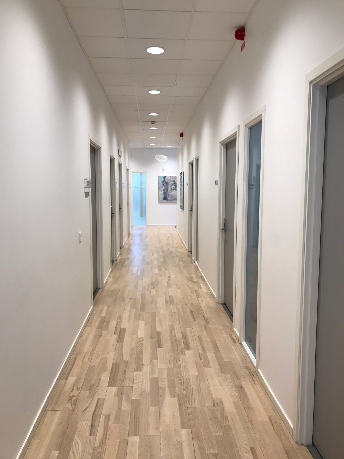 Foto på vårdcentralens vita korridor med tavlor.