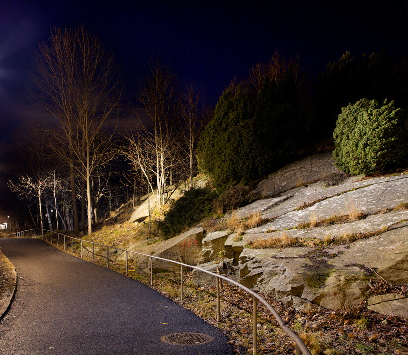 Bilden visar ett upplyst gångstråk i Biskopsgården i Göteborg, där miljön runt gångstråket ljussatts.
