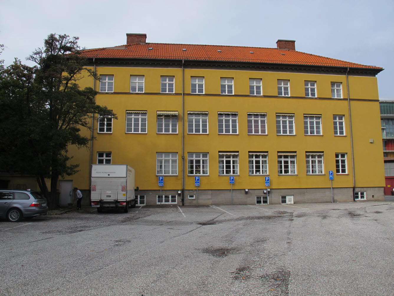 Foto på trevåningsbyggnad med gul putsad fasad med spröjsade fönster.