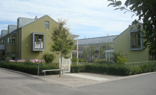 Gröna tvåvåningshus med loftgångar samlade kring en gemensam gård.