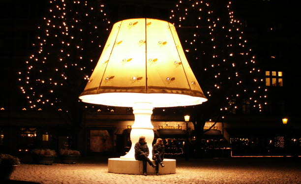 Två personer sitter på en bänk under en stor lampa. Foto: Mari Tastare