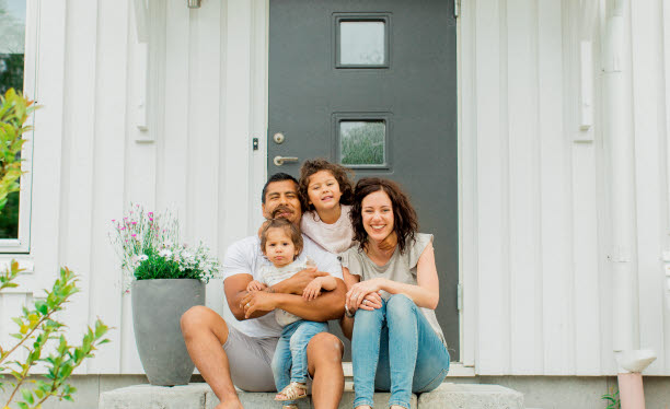 Foto på en familj framför sitt hus.