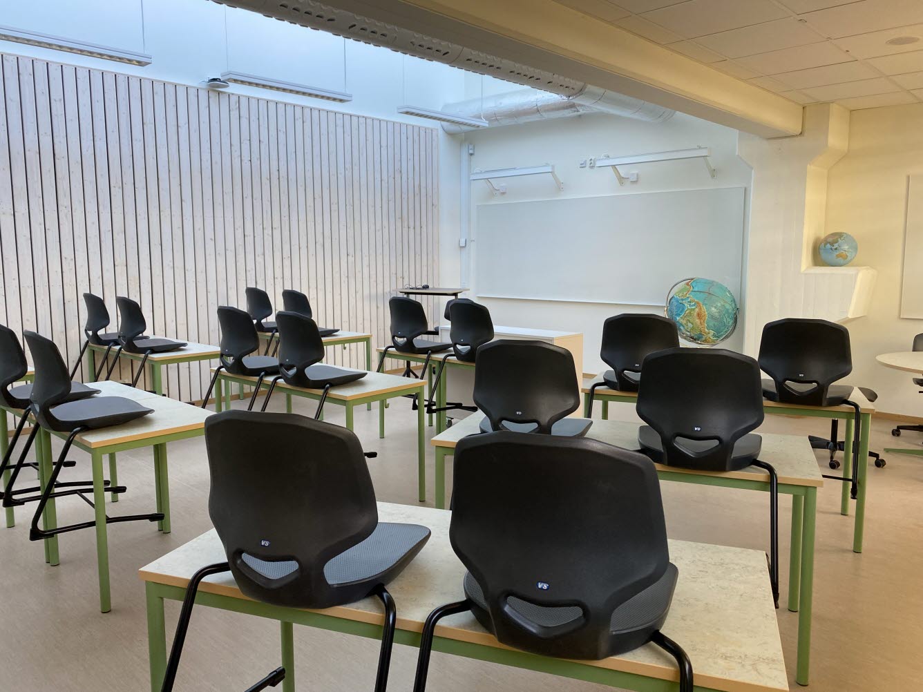 Foto på klassrum med stolar och bord.