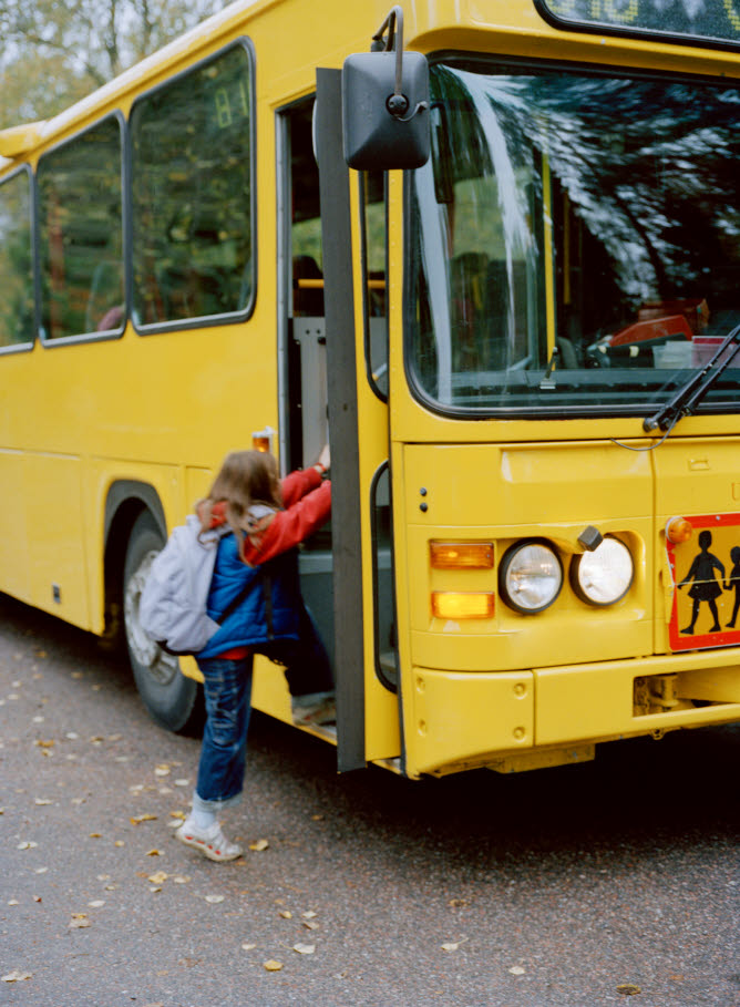 Ett barn som kliver in genom en gul buss framdörr.