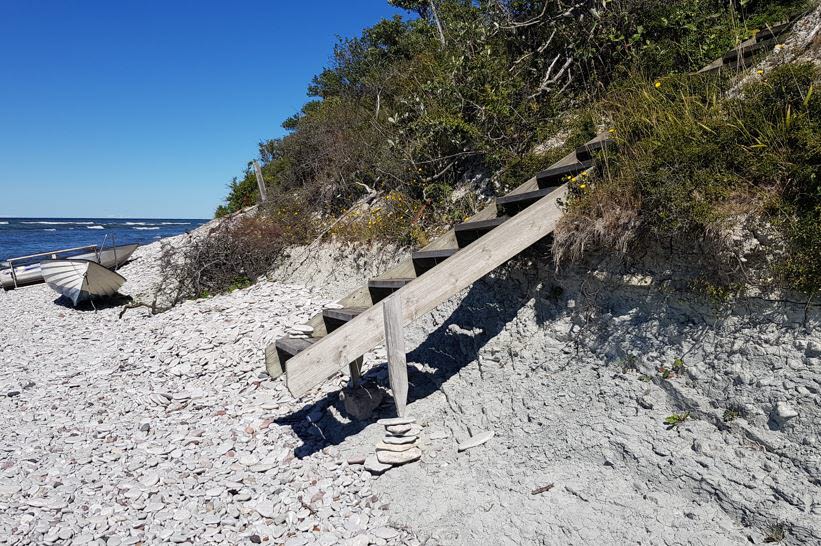 Trappa som leder ner till ett strandparti, där tappfoten hänger i luften och saknar stöd av underlget.