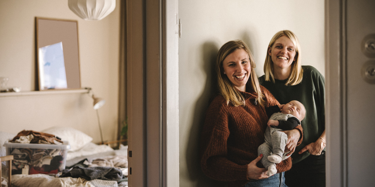 Två vuxna med en bebis i en bostad.