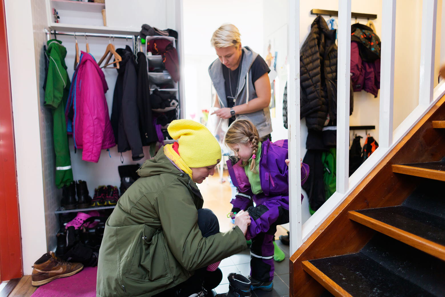 Familj tar på sig ytterkläder i hallen.
