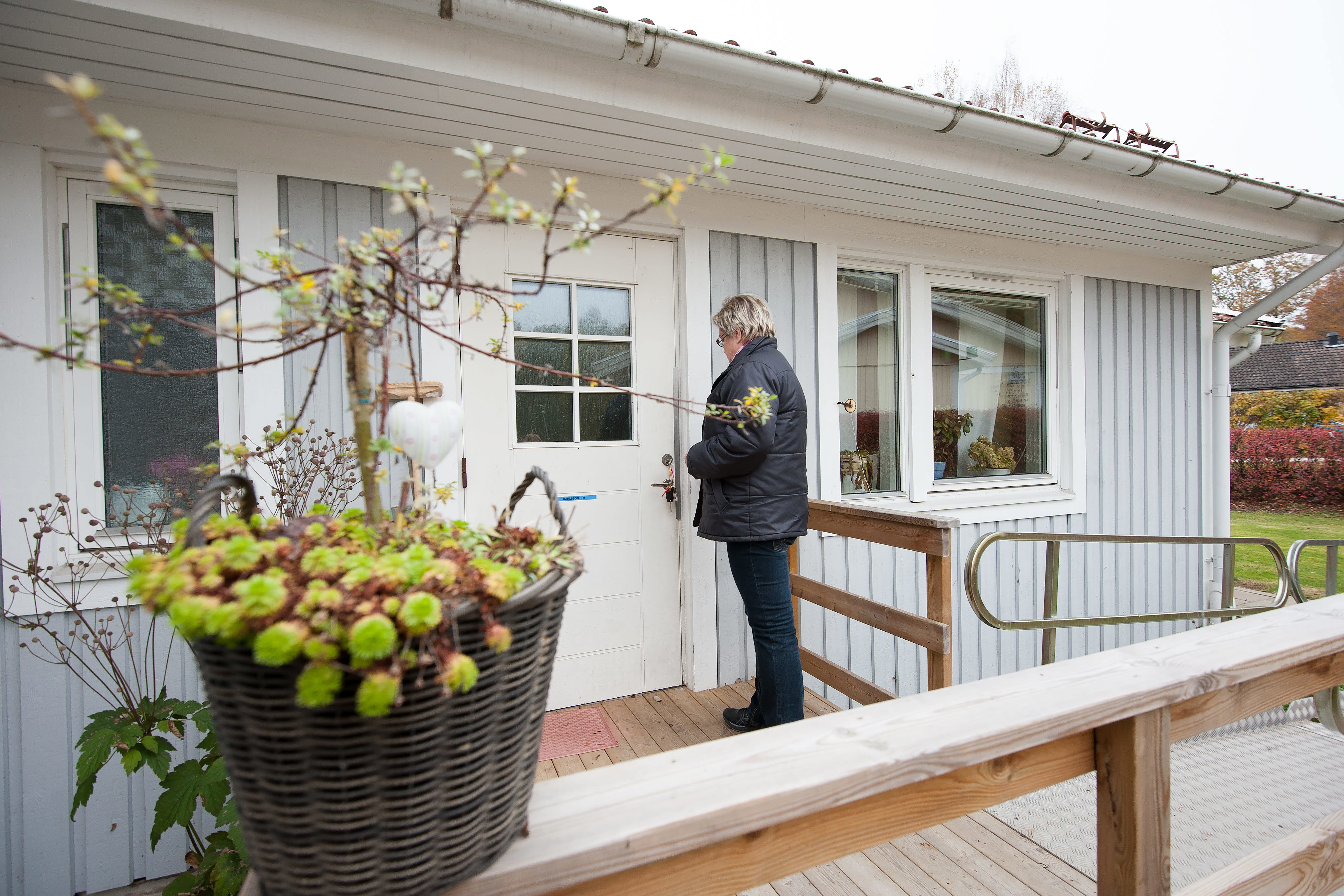 En kvinna sätter nyckeln i dörren på en villa.
