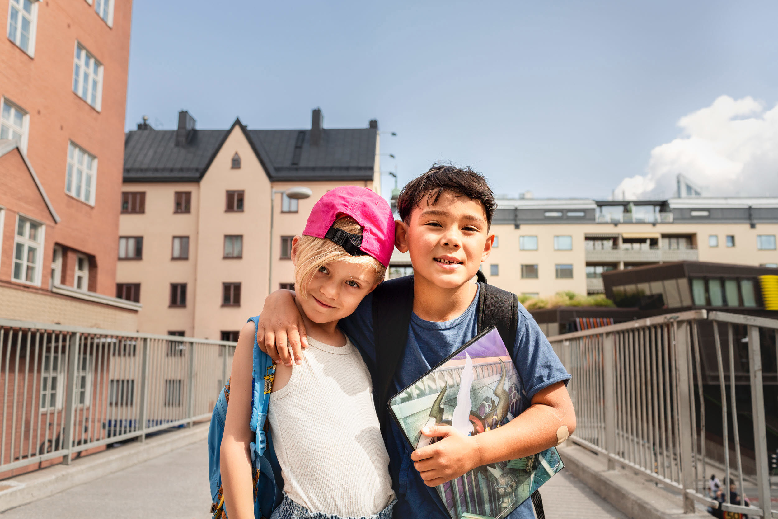 Foto på två barn som står framför några flerbostadshus.