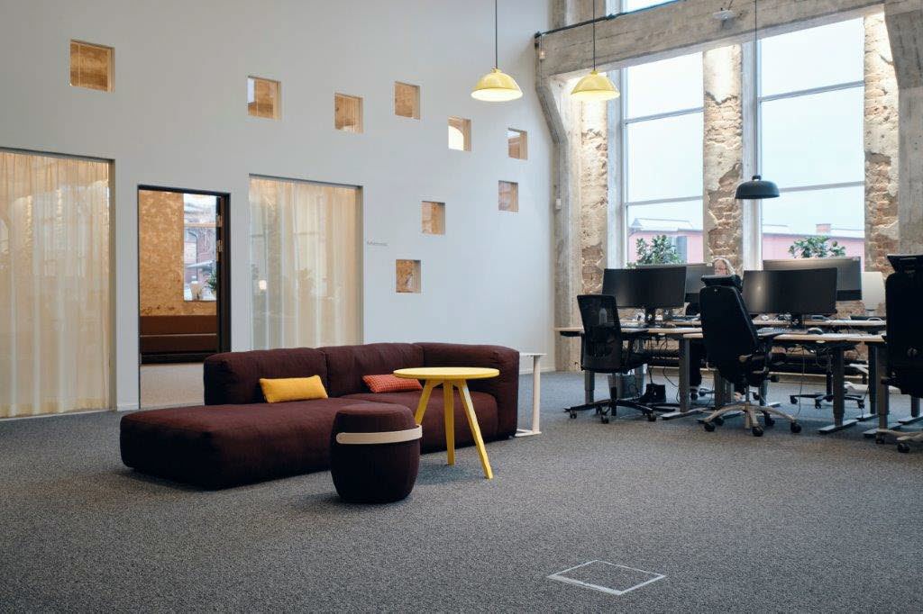 Kontorsrum med sittgrupp och kontorsplatser i ljust rum med stora fönsterytor.