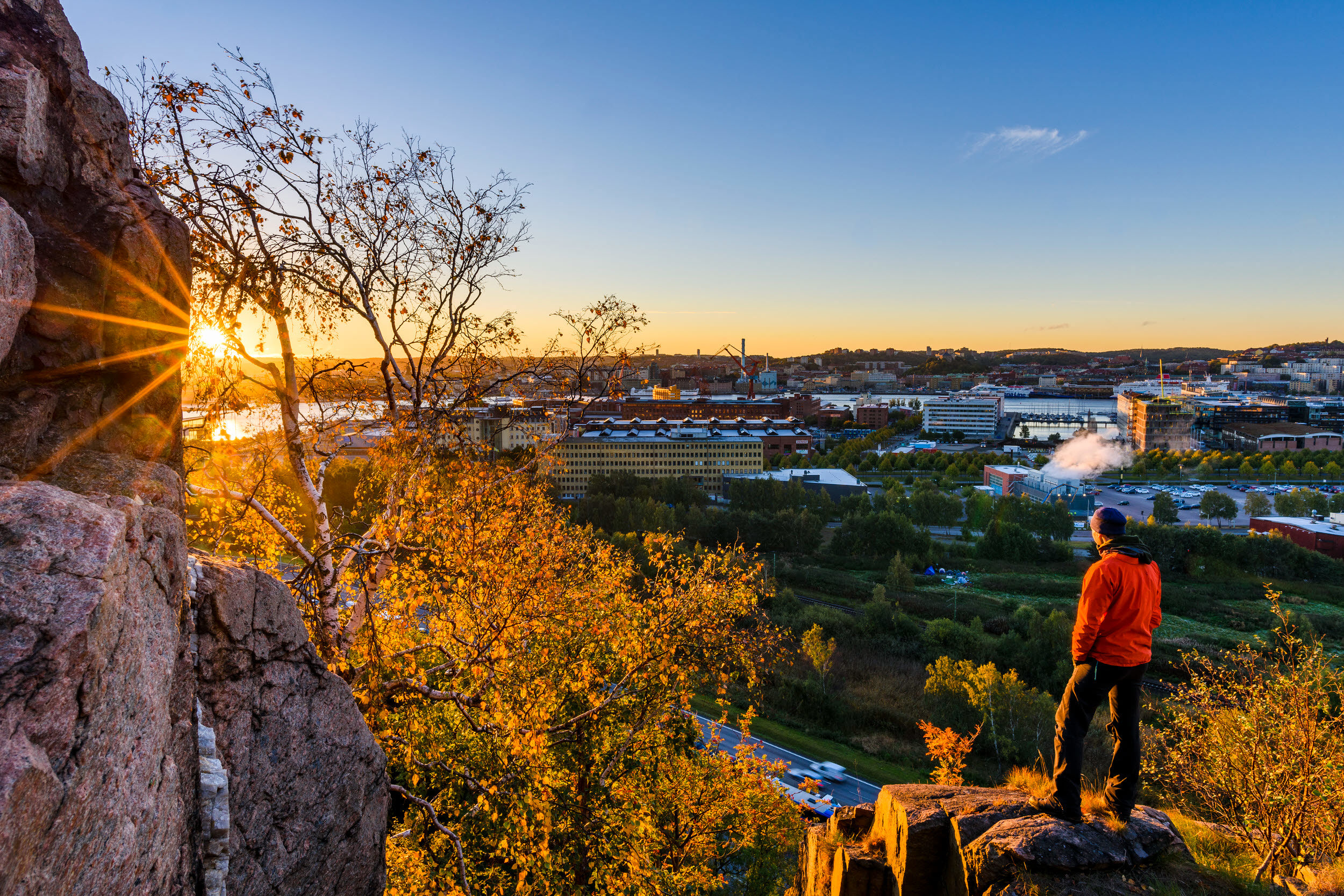 Person står på en sten och tittar ut över bebyggelse. Foto: Mikael Svensson/Scandinav