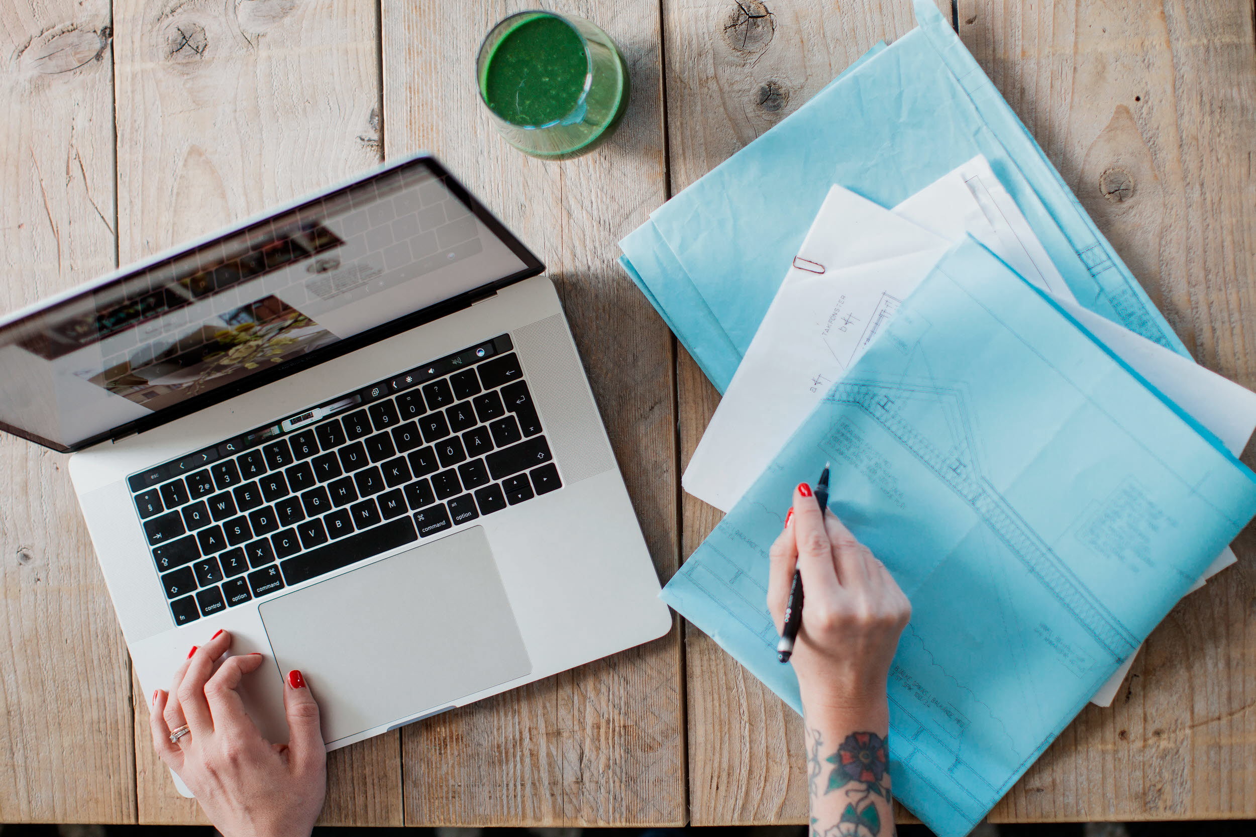 En person sitter vid en dator och skriver anteckningar på papper