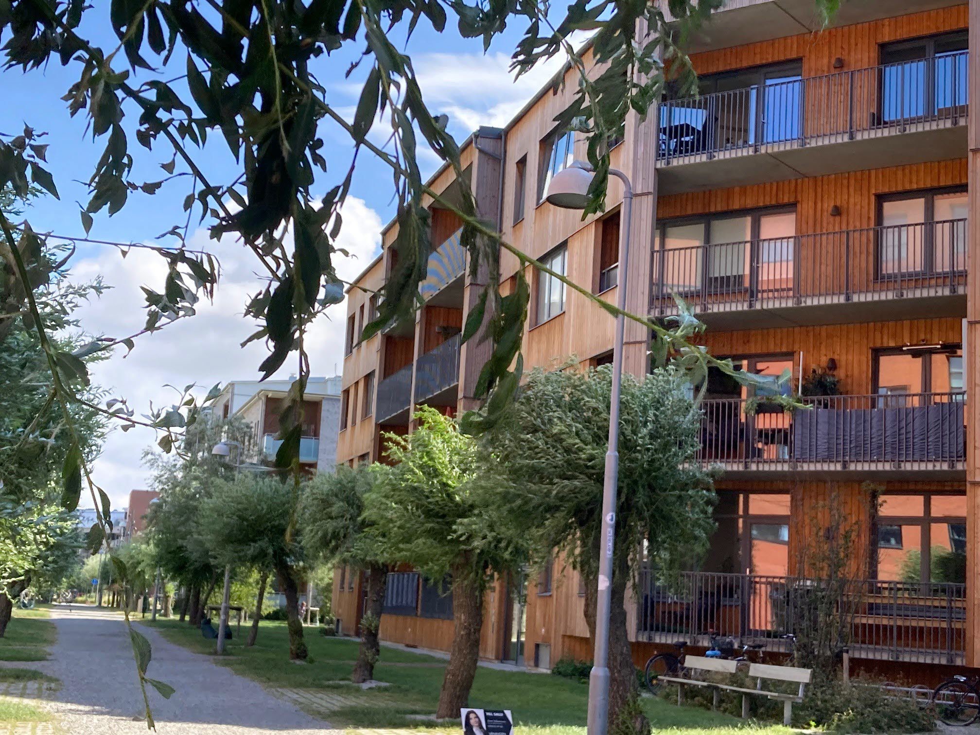 Foto av flerbostadshus i trä och grönområde.