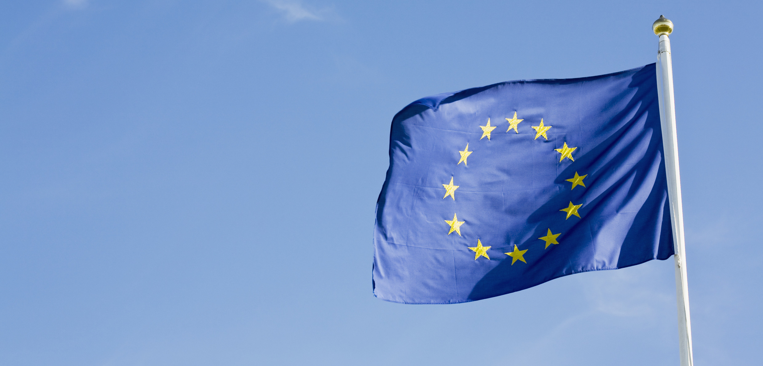 En eu-flagga som vajar i den blå himlen.