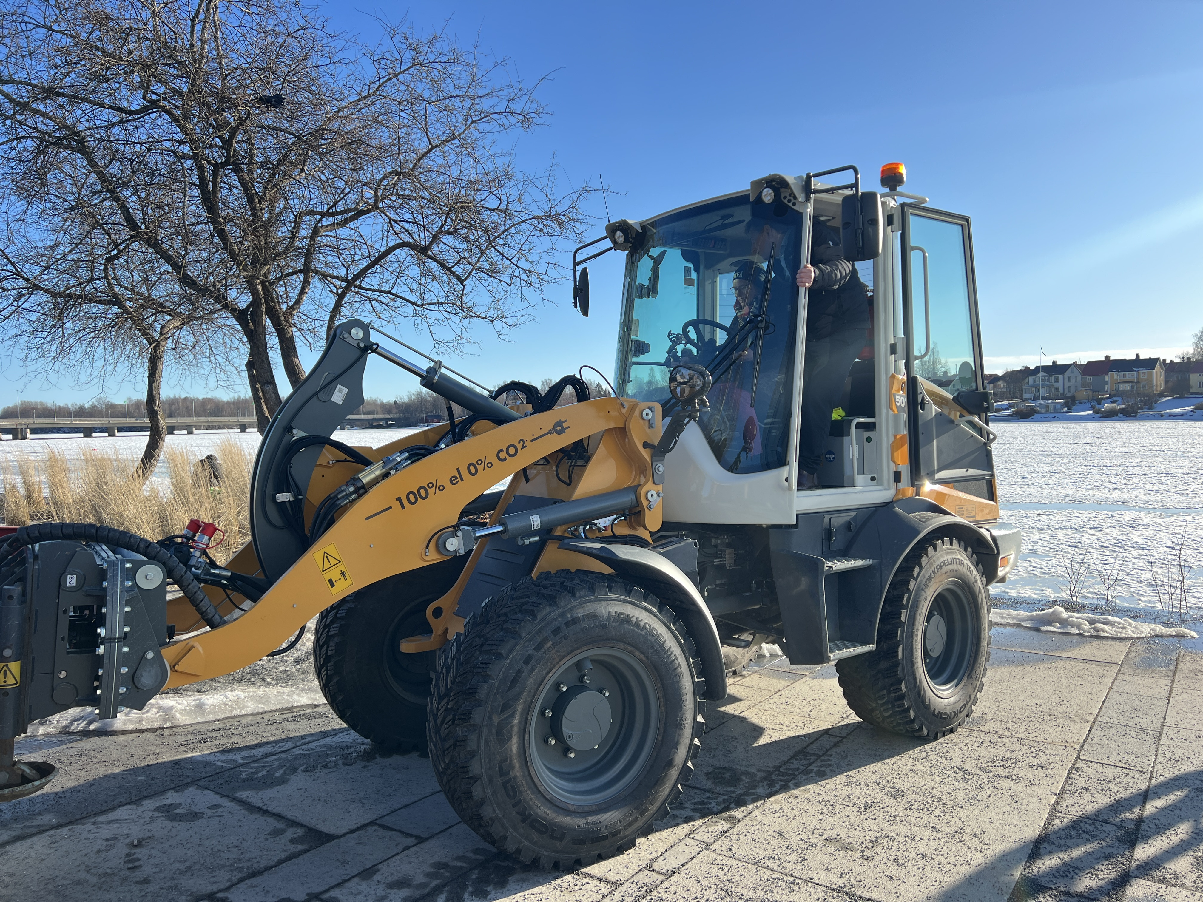 En traktor står vid en frusen sjö.