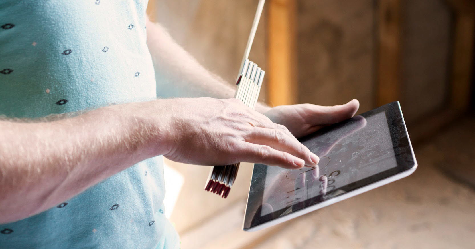 Foto på en person som navigerar med fingrarna på en ipad och håller i en tumstock.
