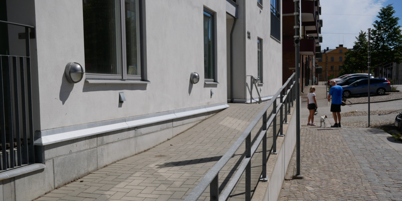 Tillgänglig lågsluttande entré utanför ett flerbostadshus.