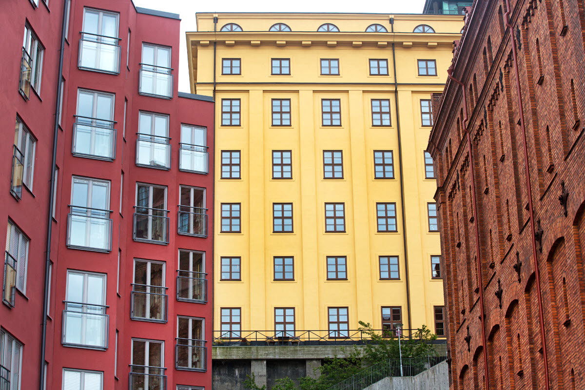 Tre husfasader, en i röd puts, en i gul puts och en i rött tegel.