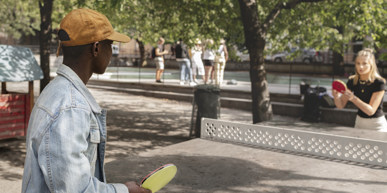 Två personer som spelar bordtennis i en park.