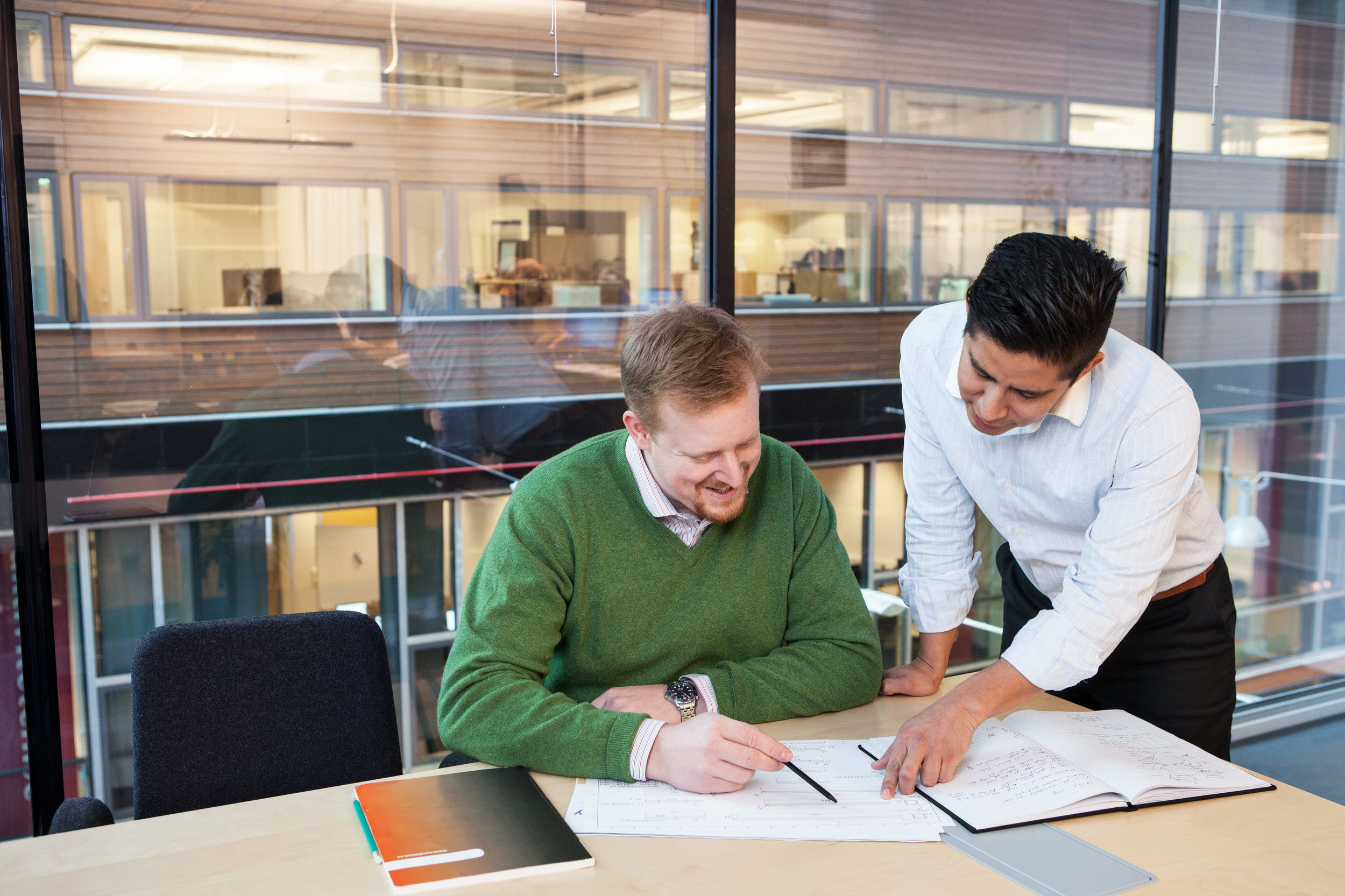 Två kollegor i ett konferensrum. Den enda står bredvid och hjälper den andra.