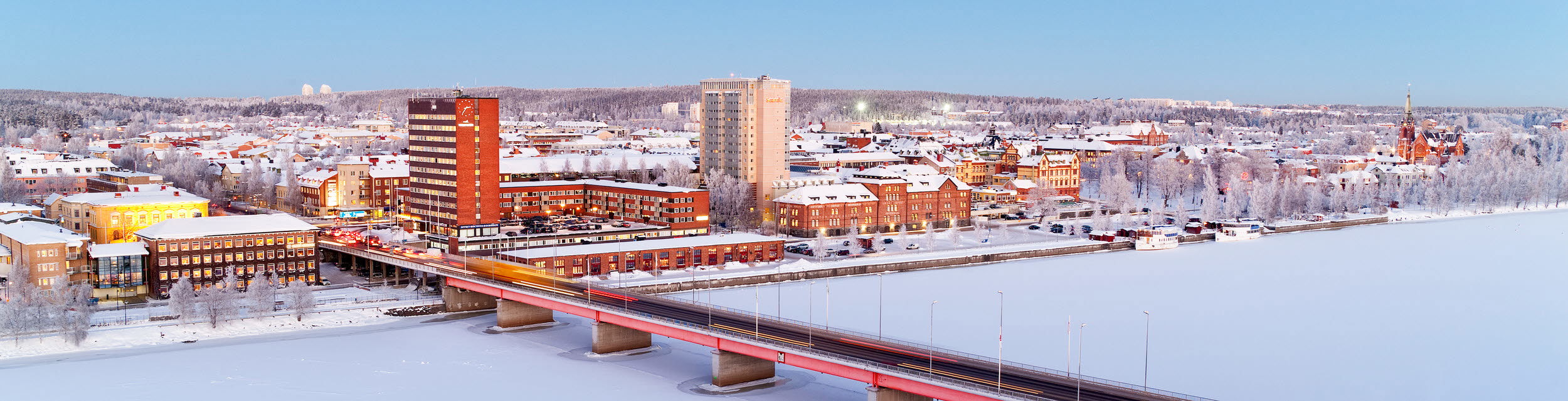 Foto av bro och stad i vinterlandskap.