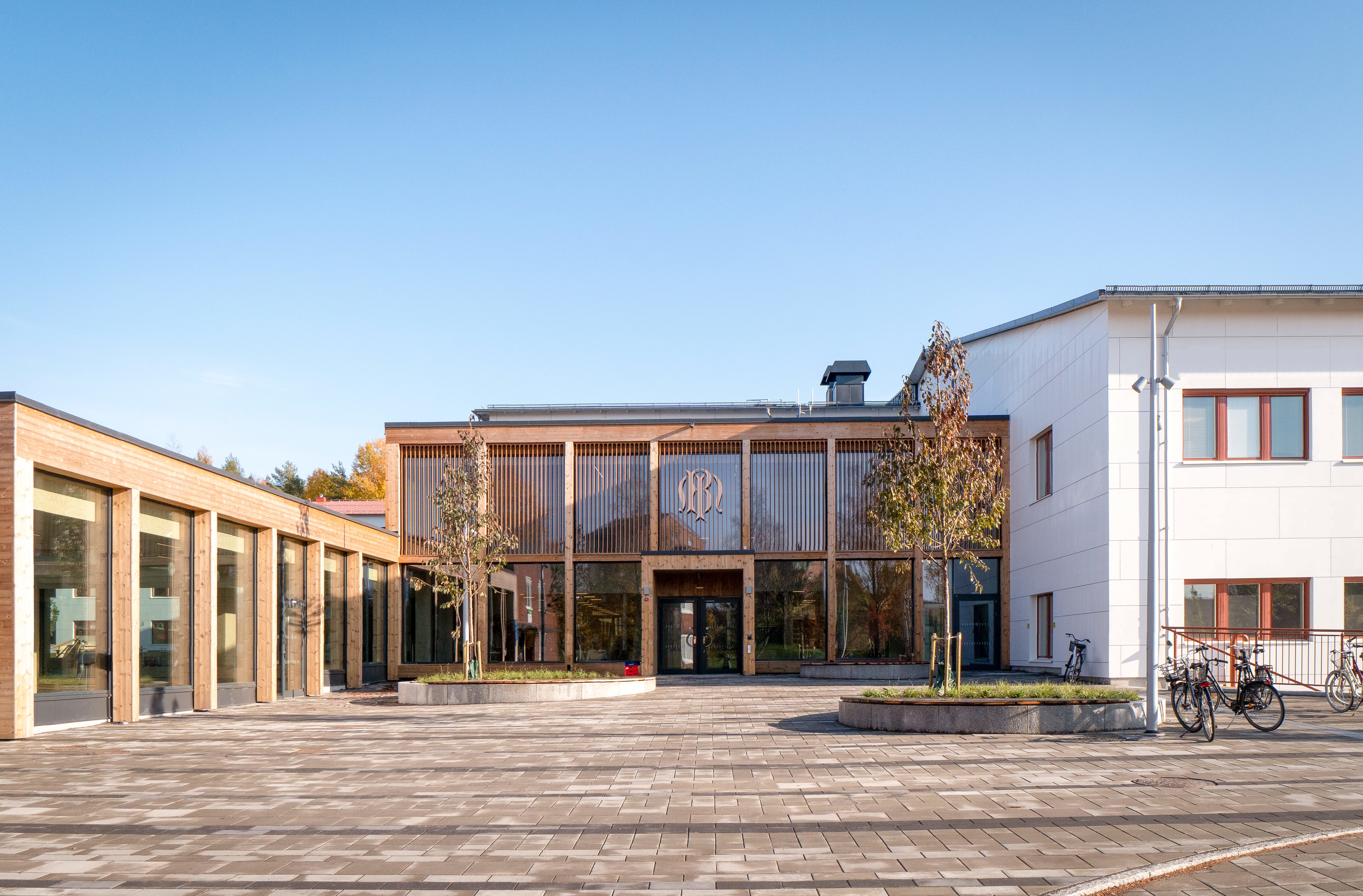 Exteriör bild på skolans tillbyggda entré vid en stenlagd yta.