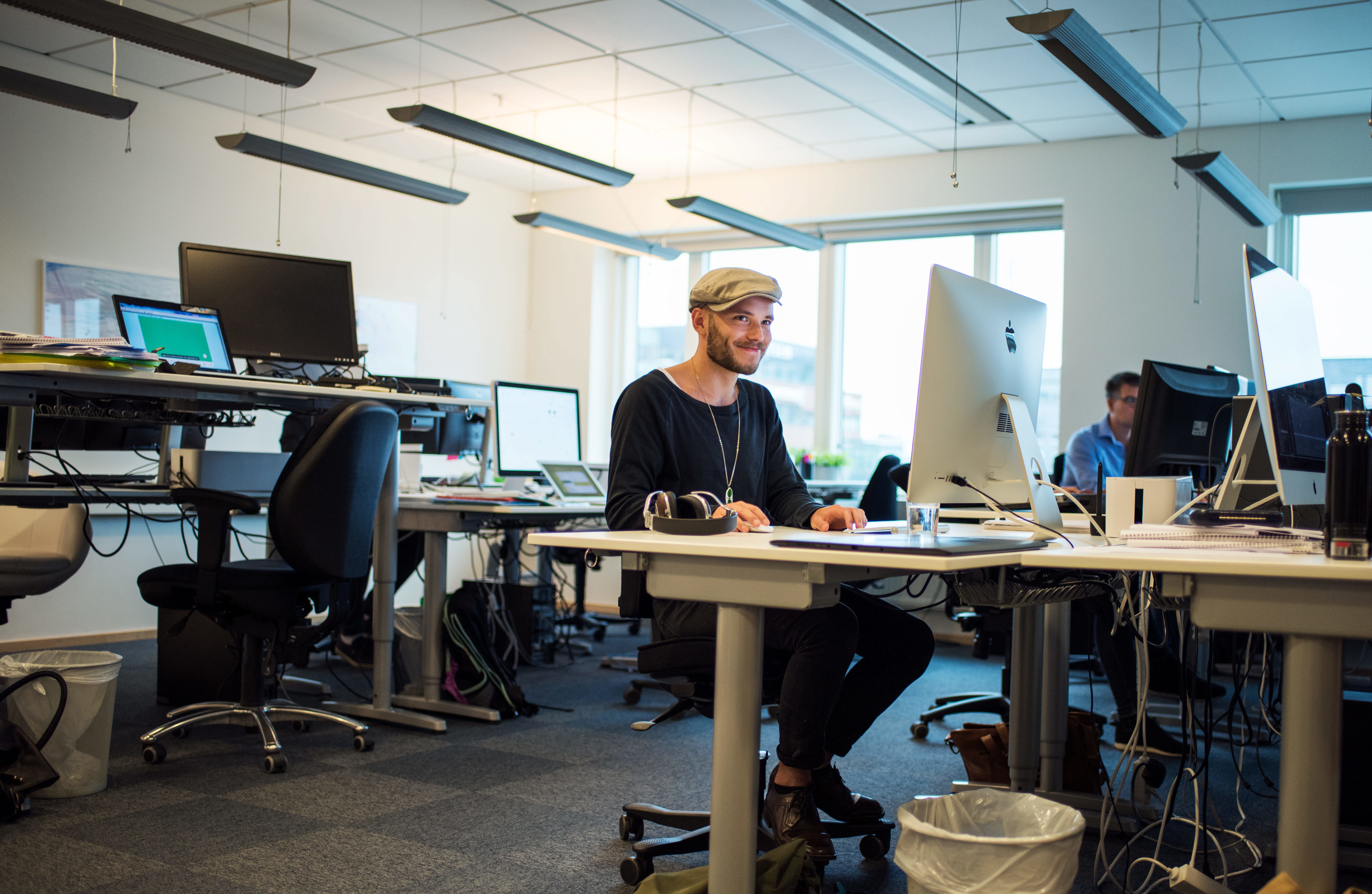 En kille sitter vid ett skrivbord och jobbar med dator.