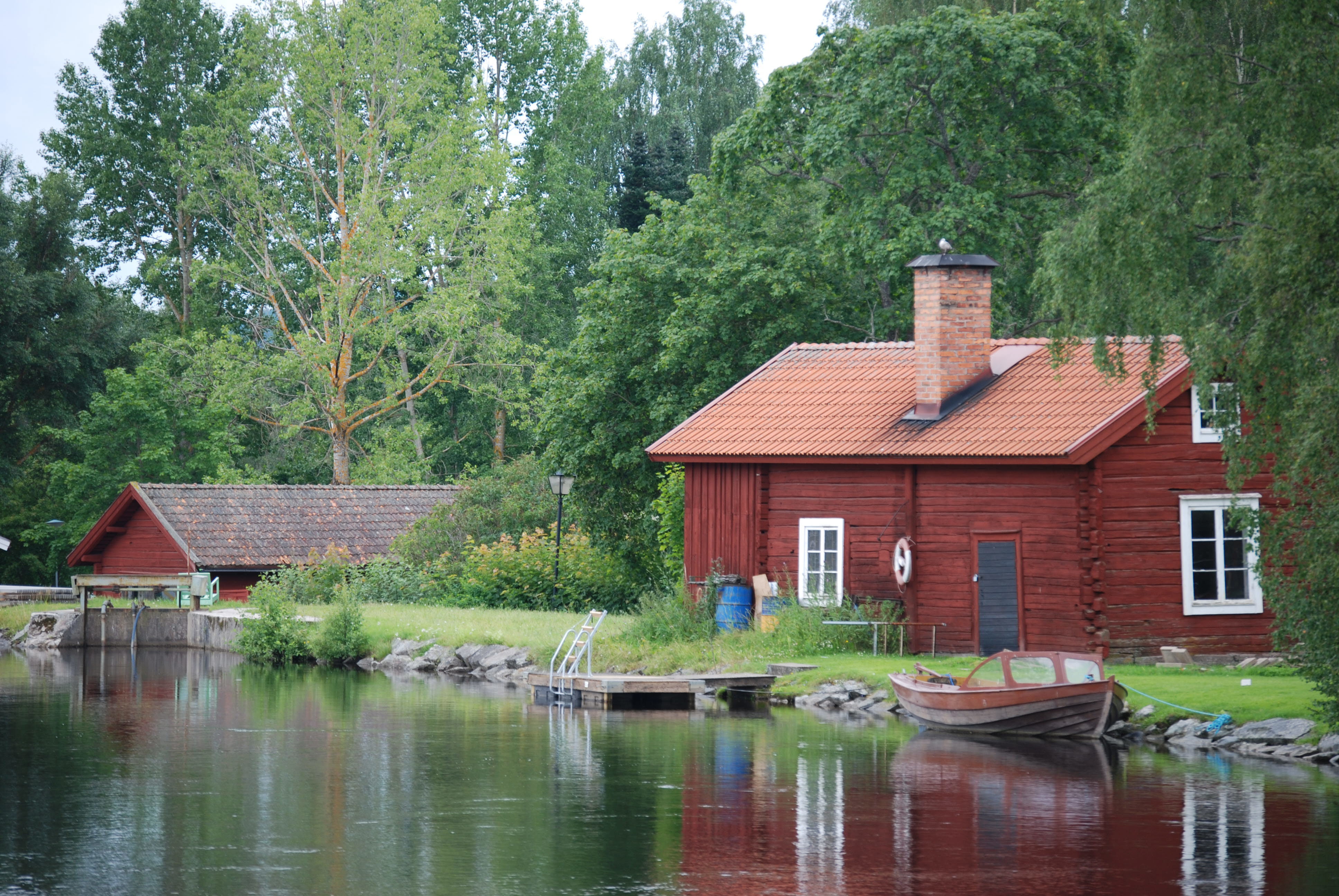 Foto på äldre byggnad i grönområde intill vatten