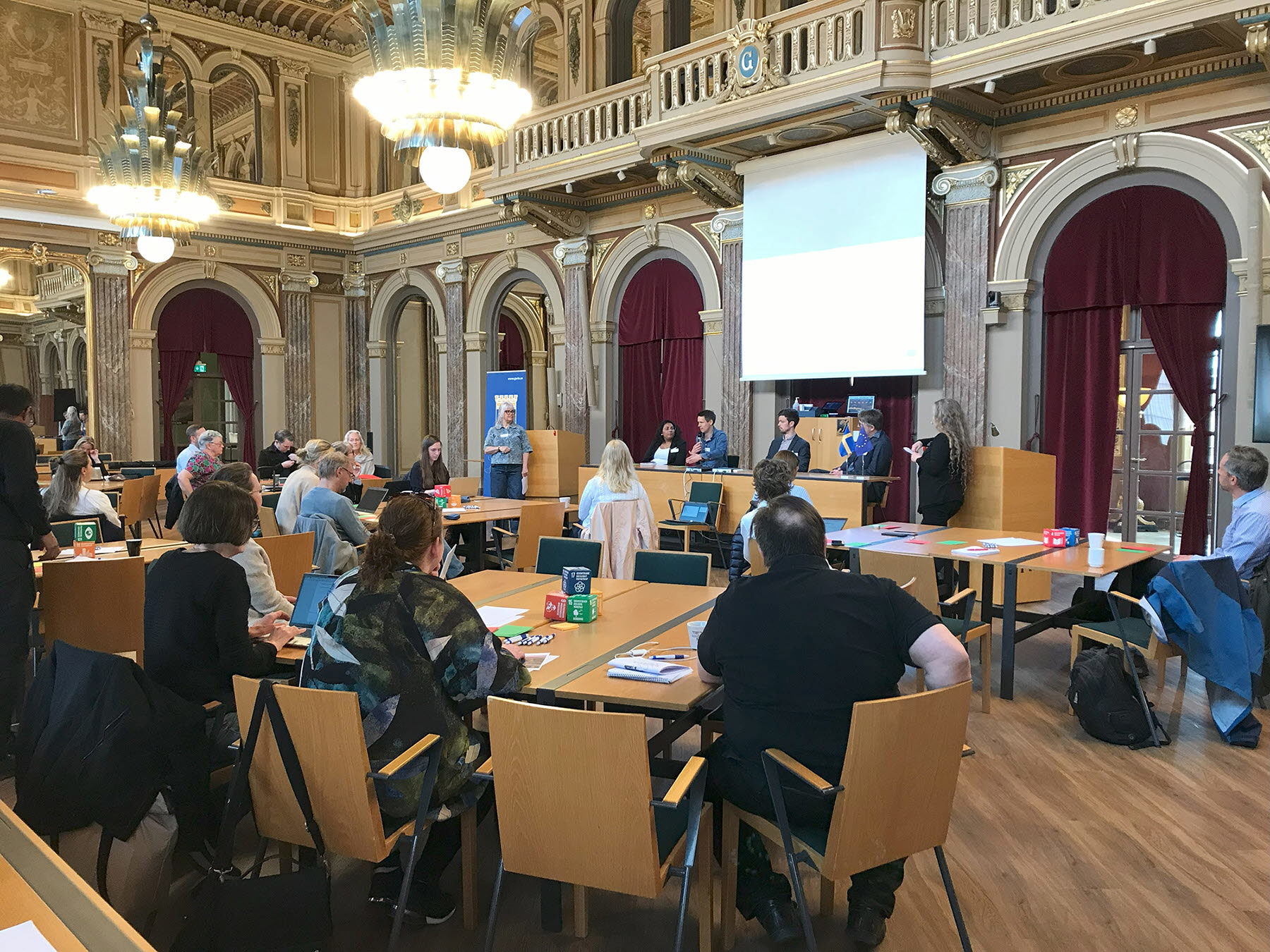 Foto taget av ett panelsamtal mellan flera människor i en sal.