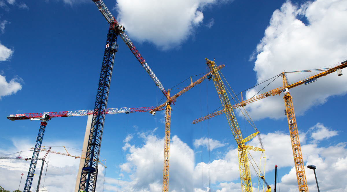 Byggkranar mot en blå himmel med små moln. Foto: Hans Ekestang