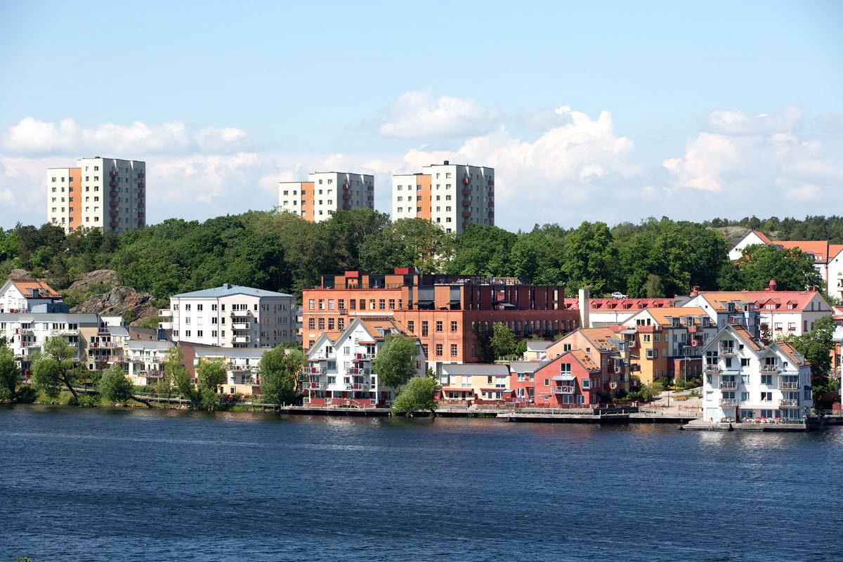 Flerbostadshus i olika storlekar och höjder samt skogspartier som finns bakom en vattenlinje.