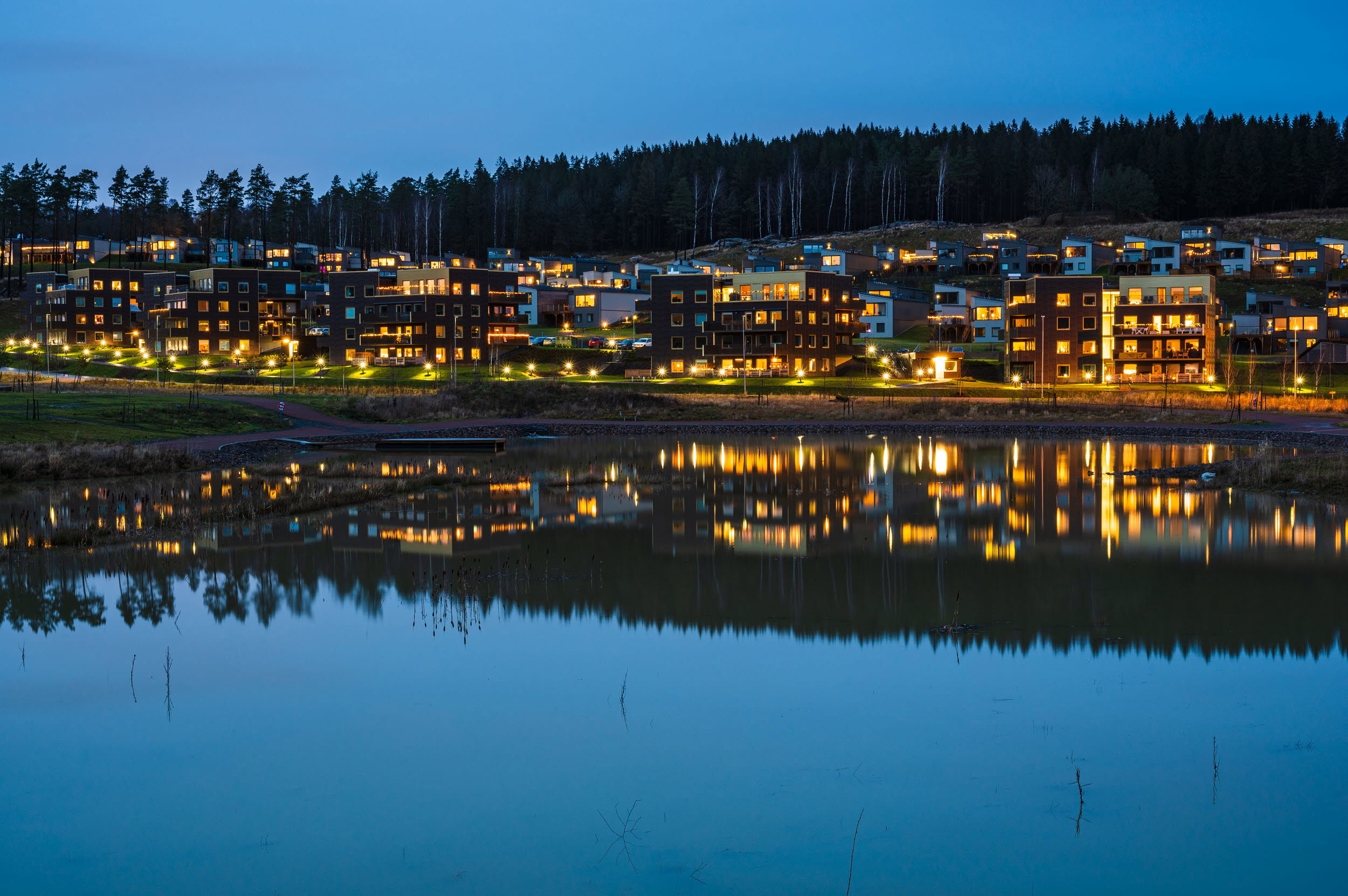 Foto av upplyst stadsdel vid vatten.