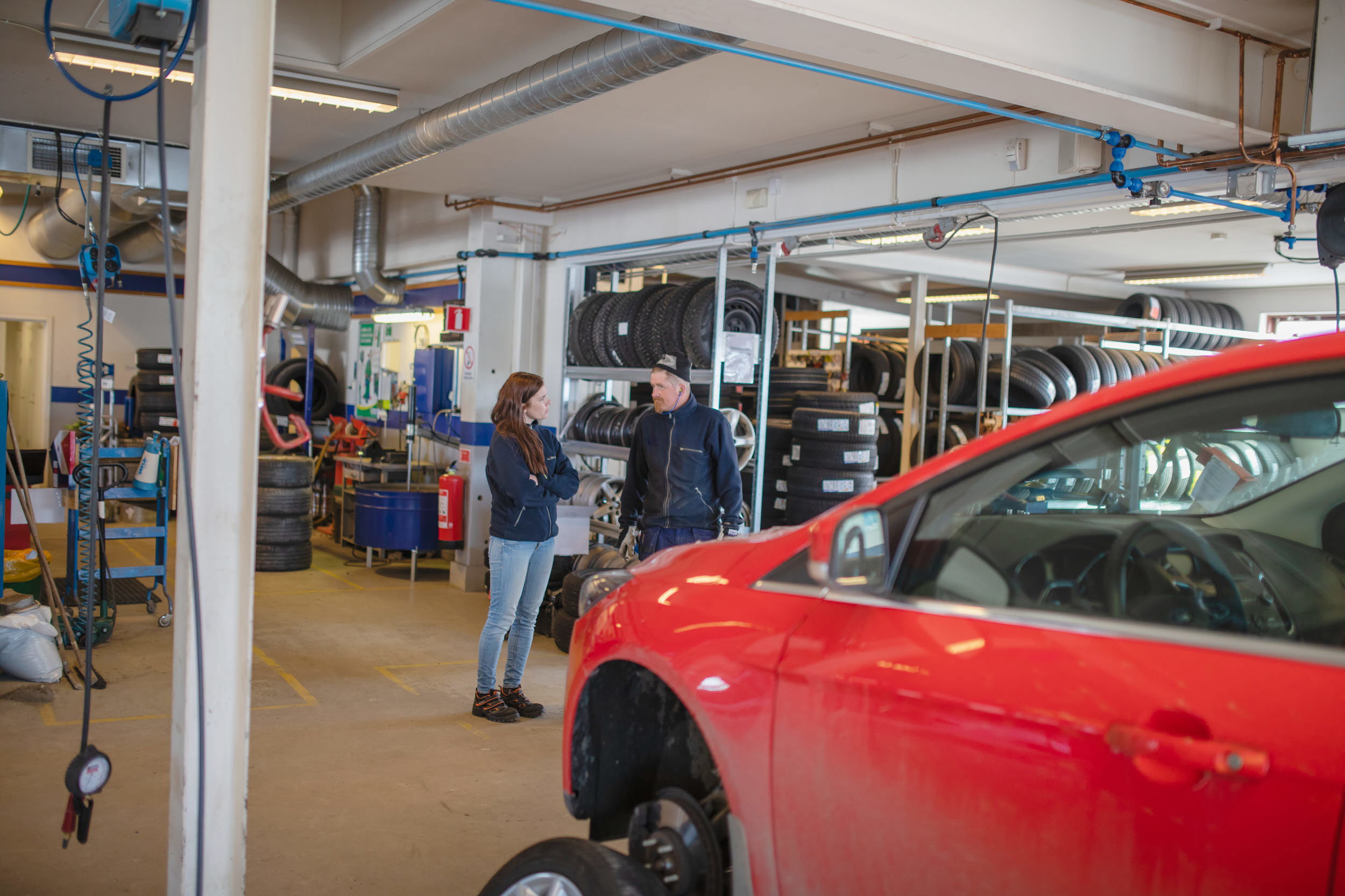 En man och en kvinna står och pratar på en bilverkstad.