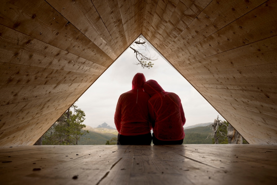 Bild på två personer som sitter lutade mot varandra, tak och golv bildar en trekant.