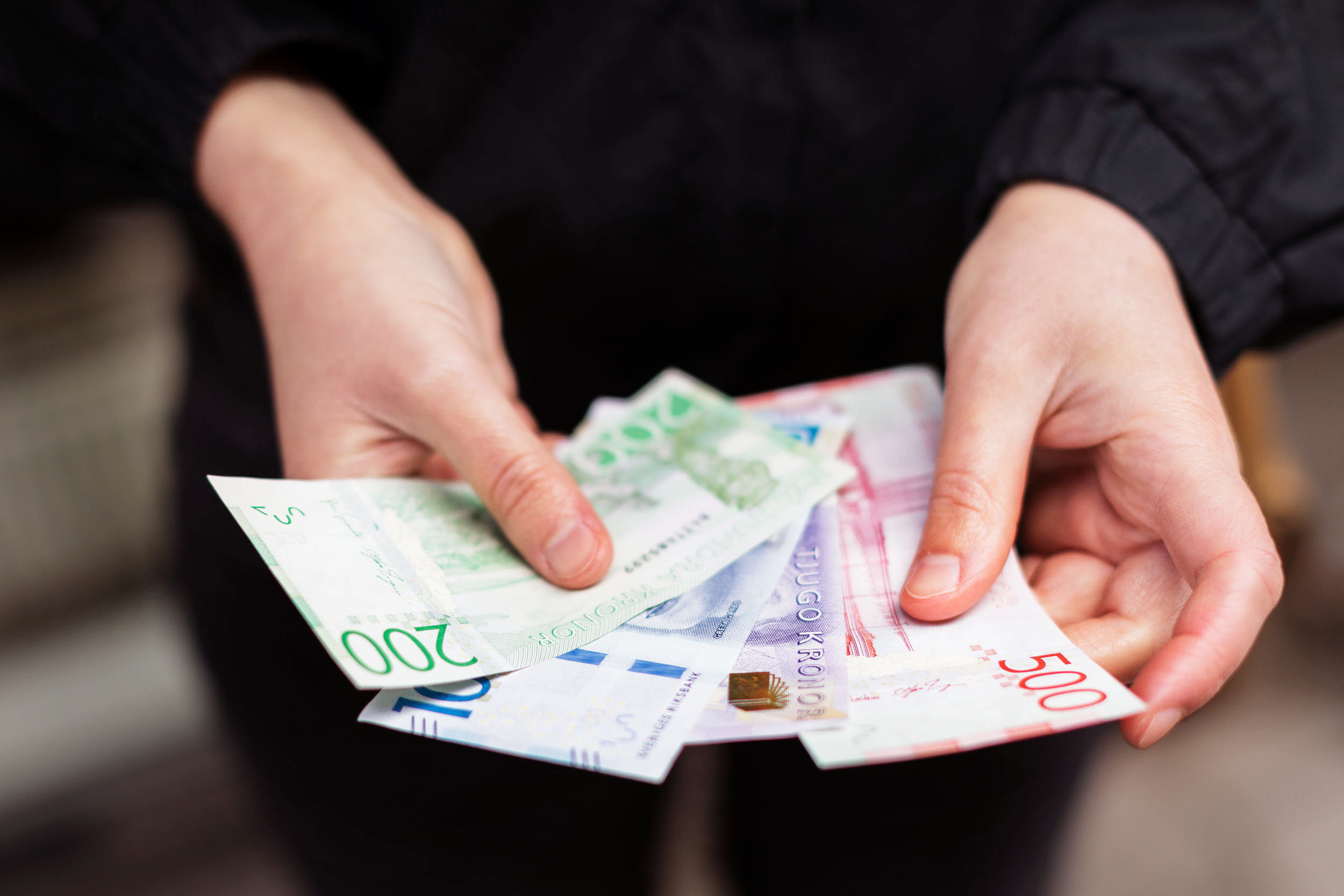 Händer som håller i sedlar.