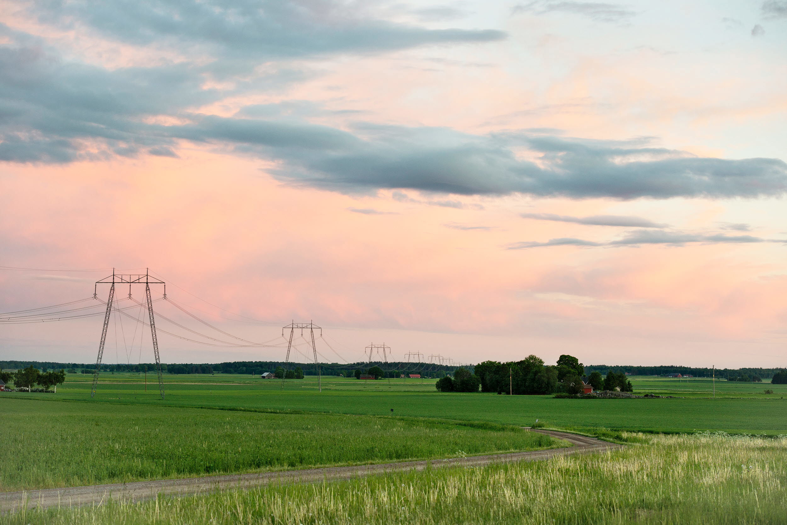 Kraftledning i skymning i öppet landskap.