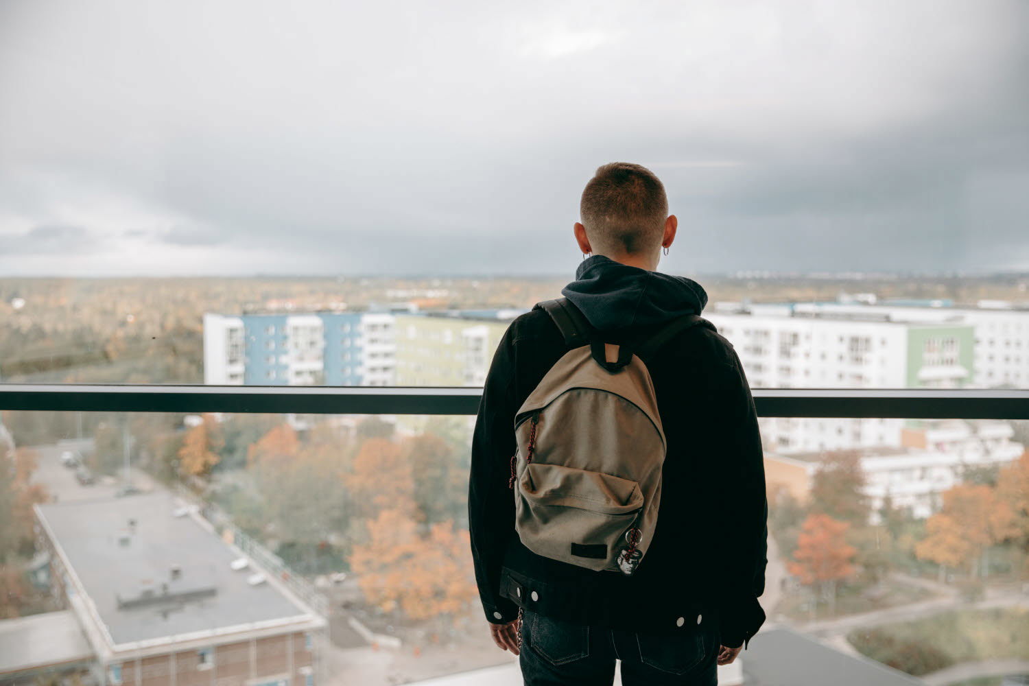 Ett barn står på en balkong och ser ut över ett bostadsområde. Foto: Scandinav