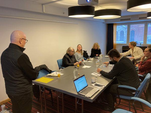 Foto av konferensbord med människor som sitter runt.