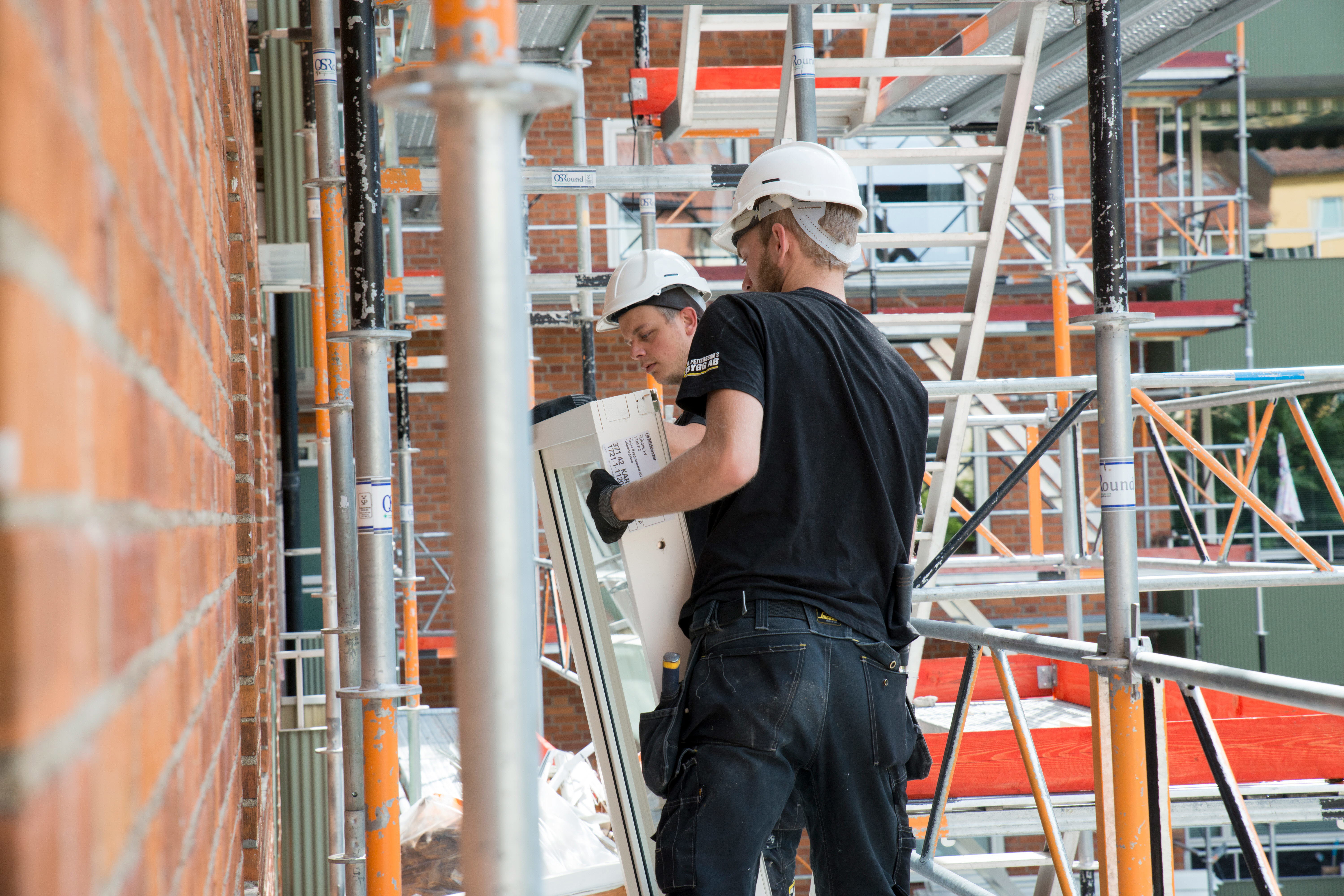 Två personer som byter fönster på ett flerbostadshus. Foto: Franz Feldmanis.