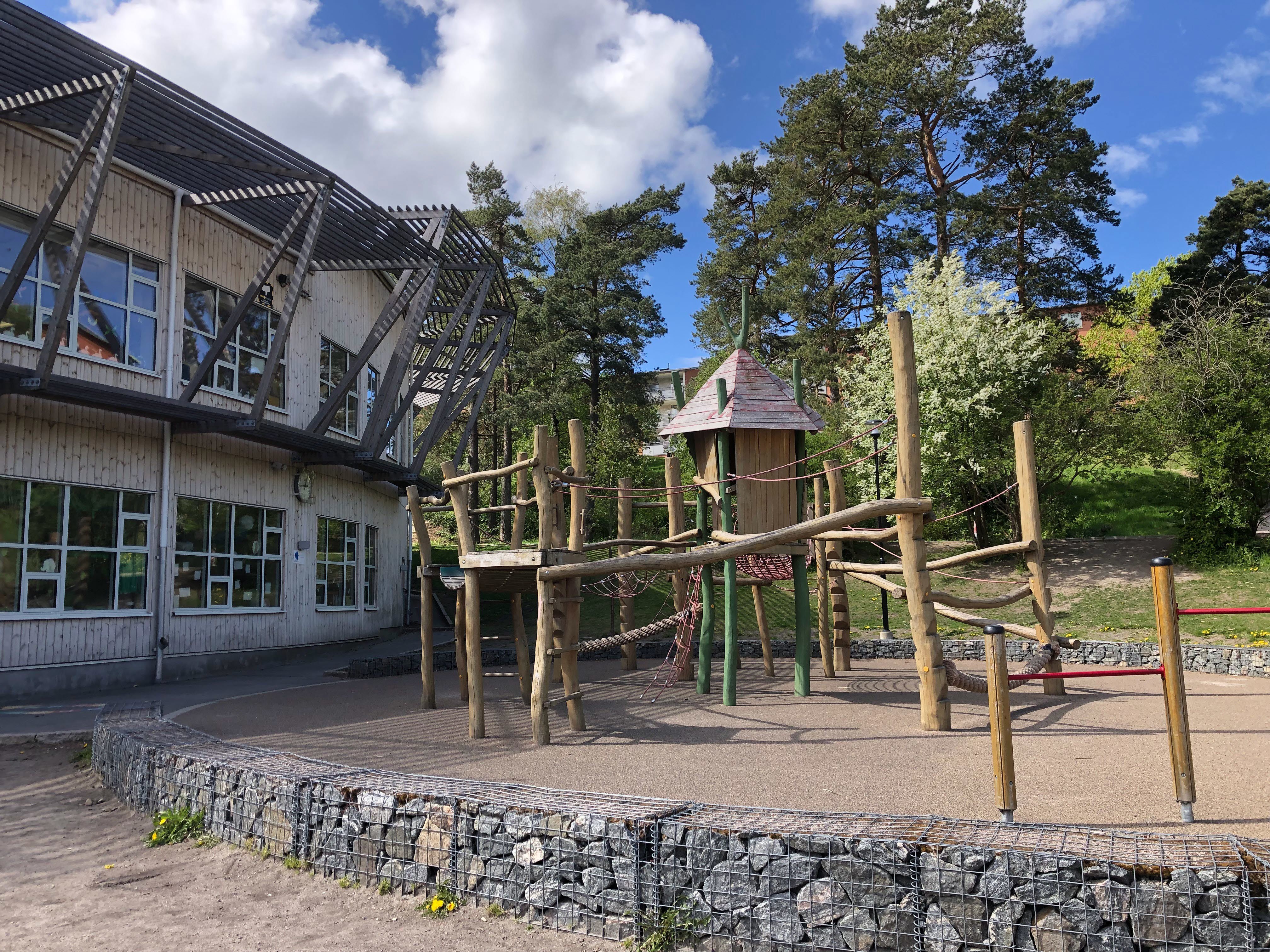 Klätterställning med landgångar och ett litet torn som står på en skolgård.
