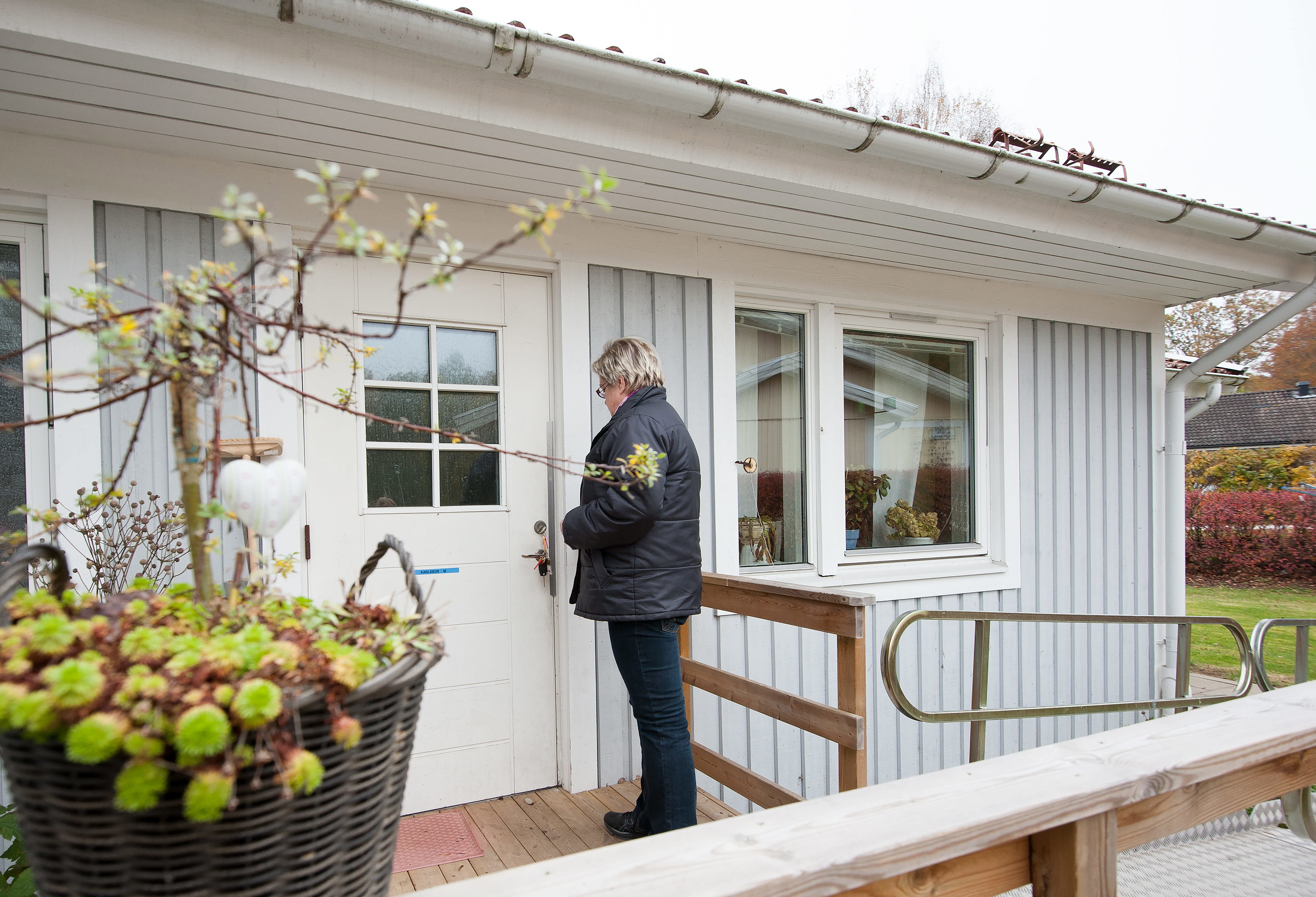 En kvinna sätter nyckeln i dörren på en enplansvilla.