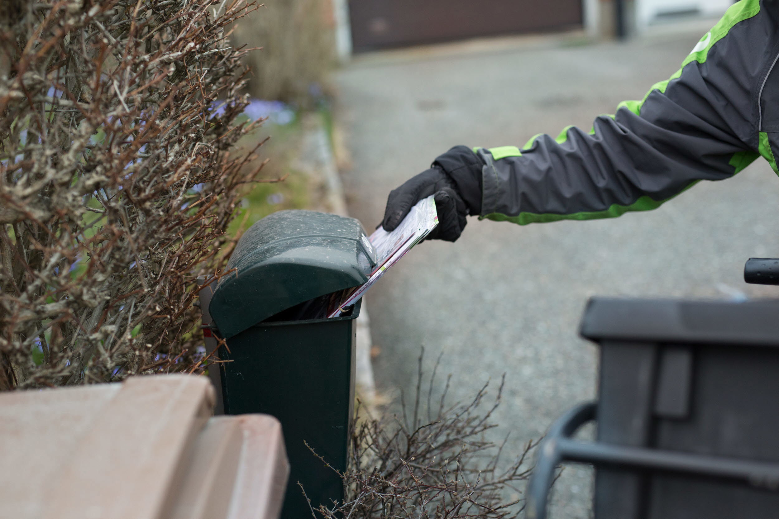 Post lämnas i en brevlåda av en brevbärare.