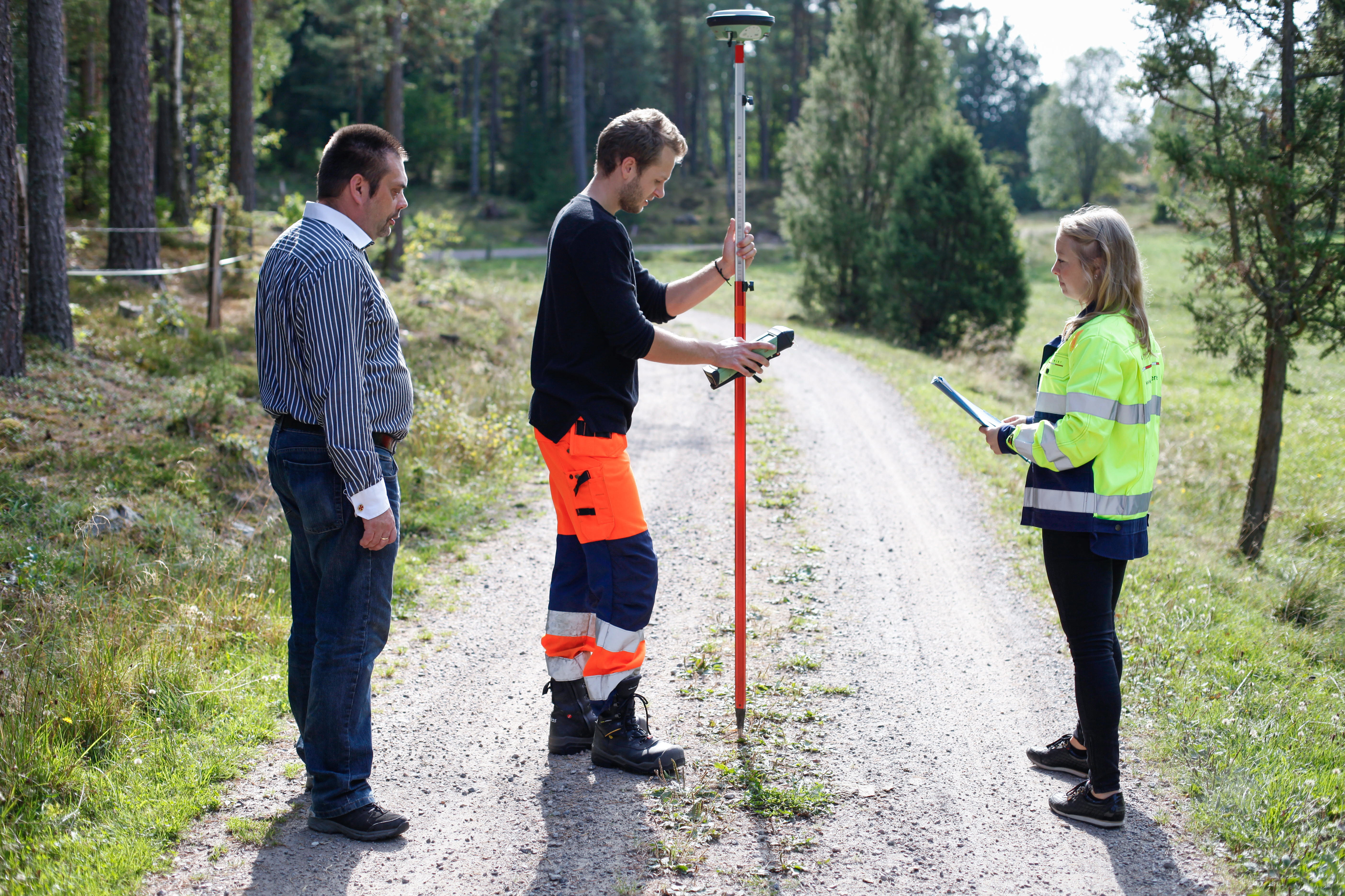 Lantmäteriutrustning med tre personer.