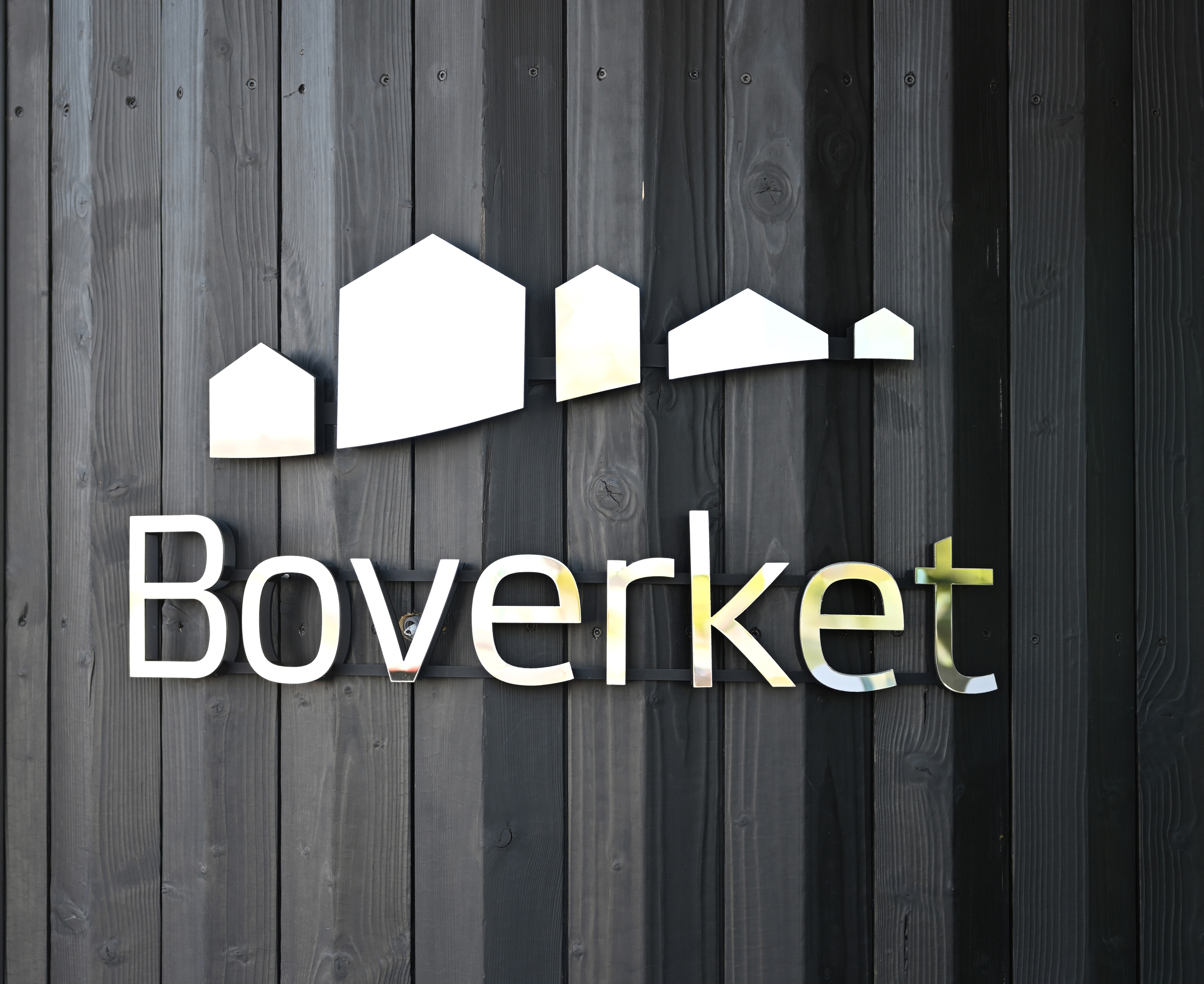 En svart trävägg med en metallskylt med ordet Boverket