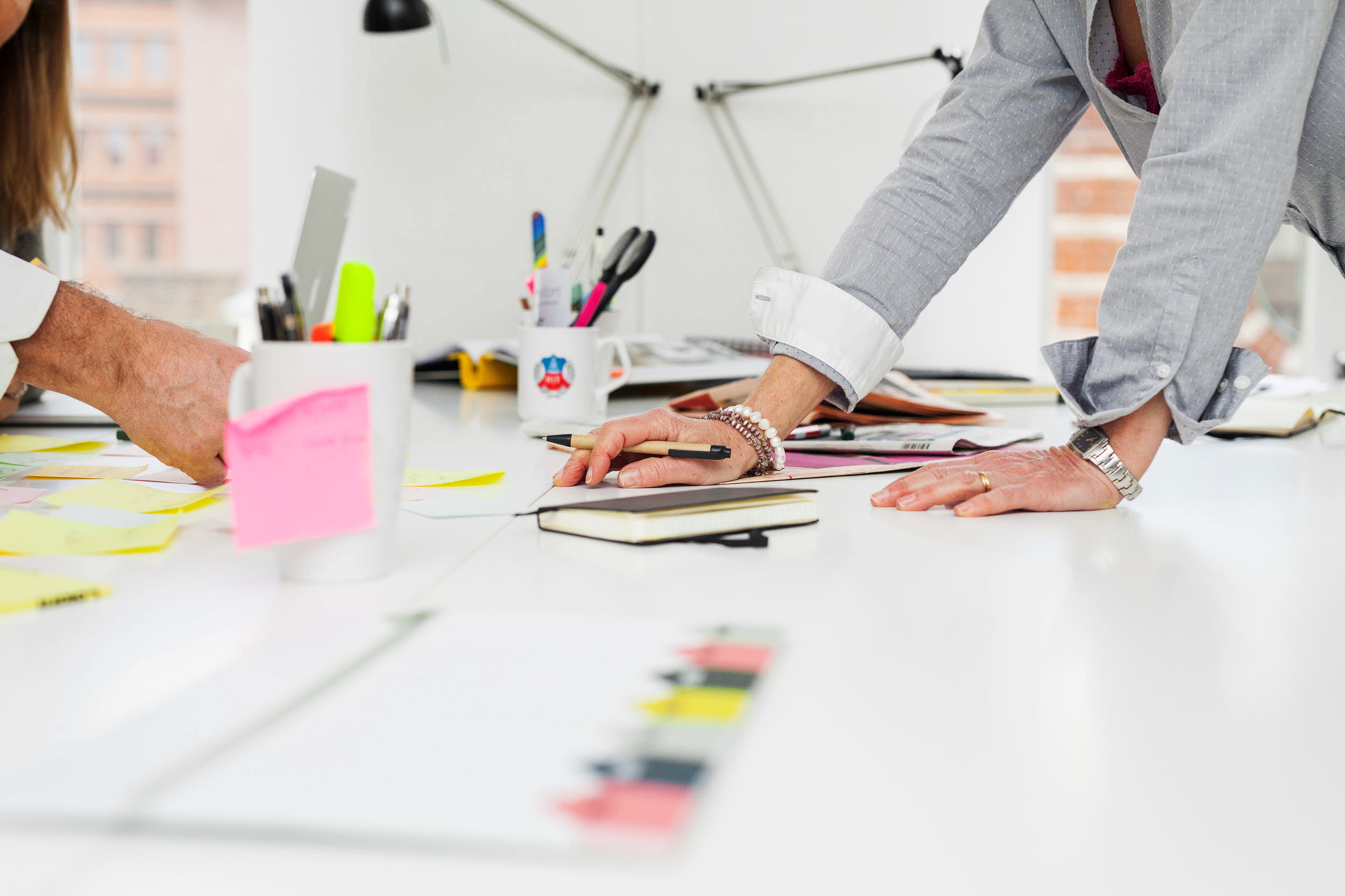 Två personer jobbar med post-its vid ett skrivbord.