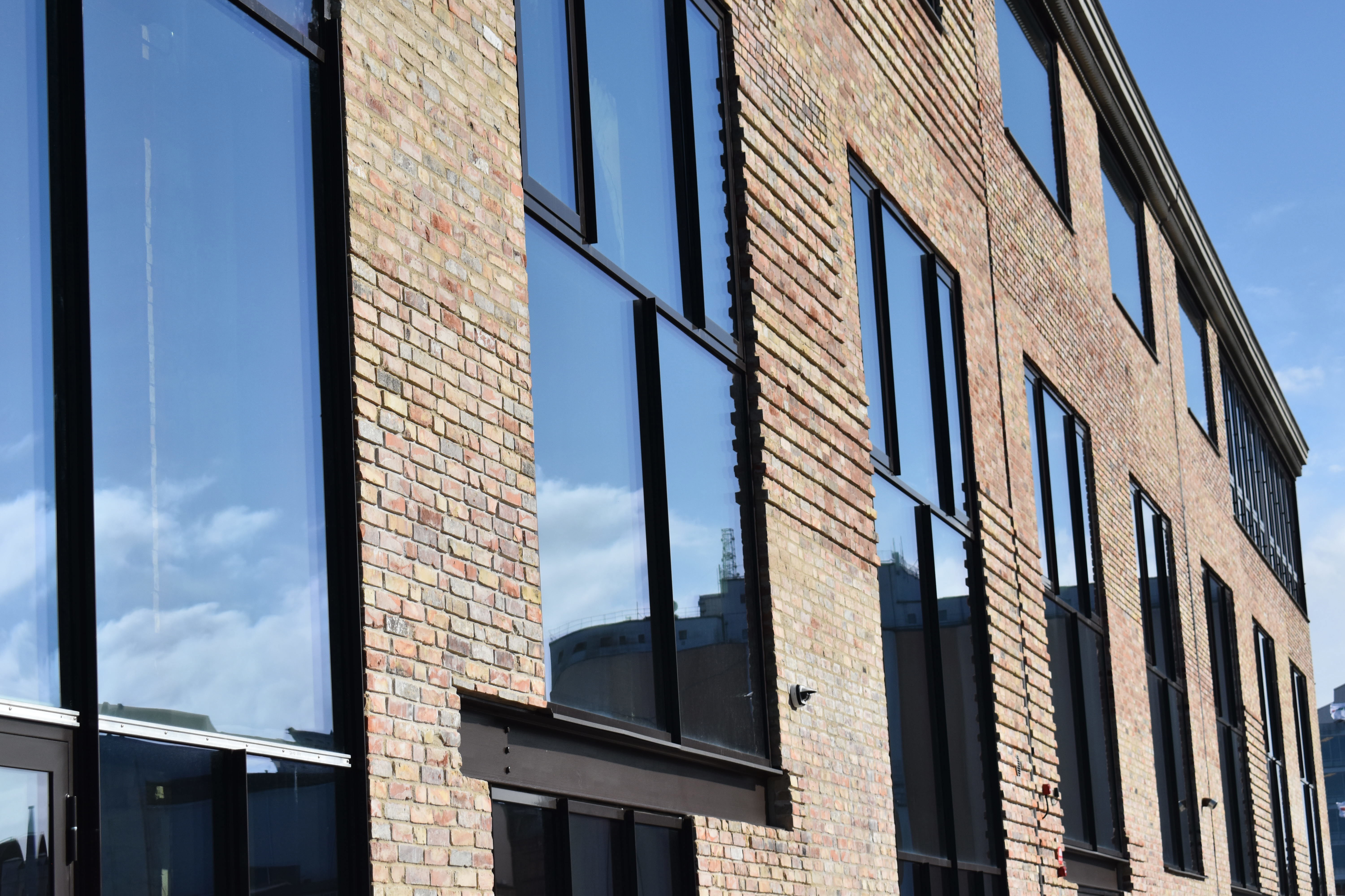 Fasad i tegel med stora glasfönster. 