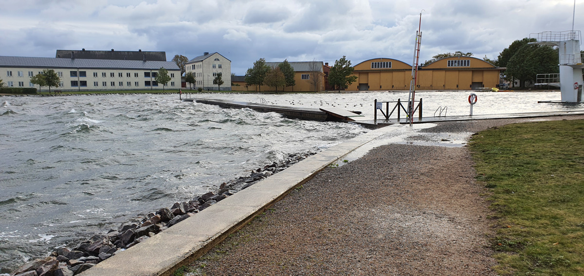 Översvämning efter mycket regn i en stad, promenadstig och byggnader.