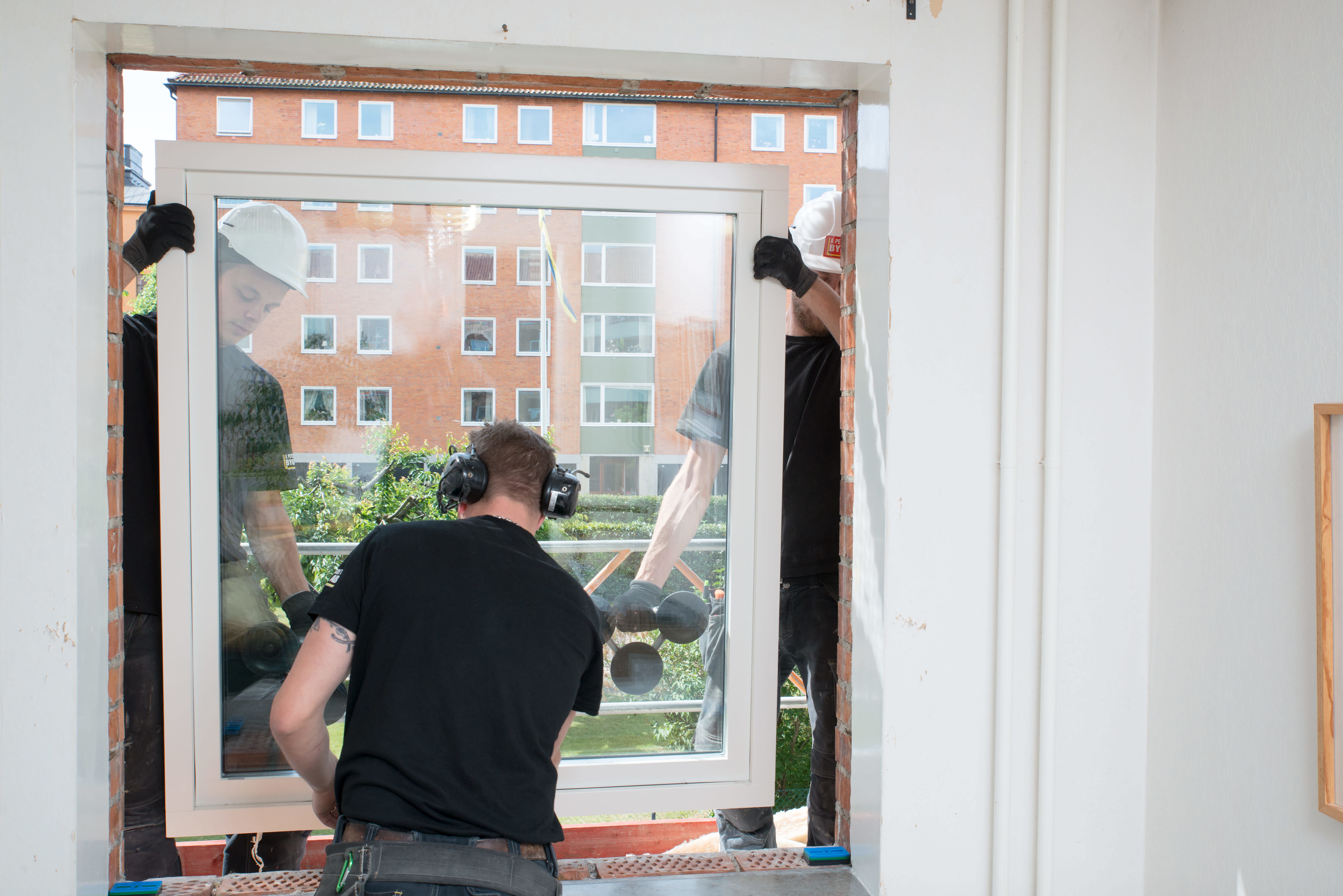 Tre snickare byter ett fönster. Foto: Franz Feldmanis