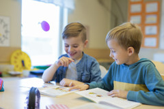 Foto på två barn som sitter vid ett bord och bläddrar i varsin bok.