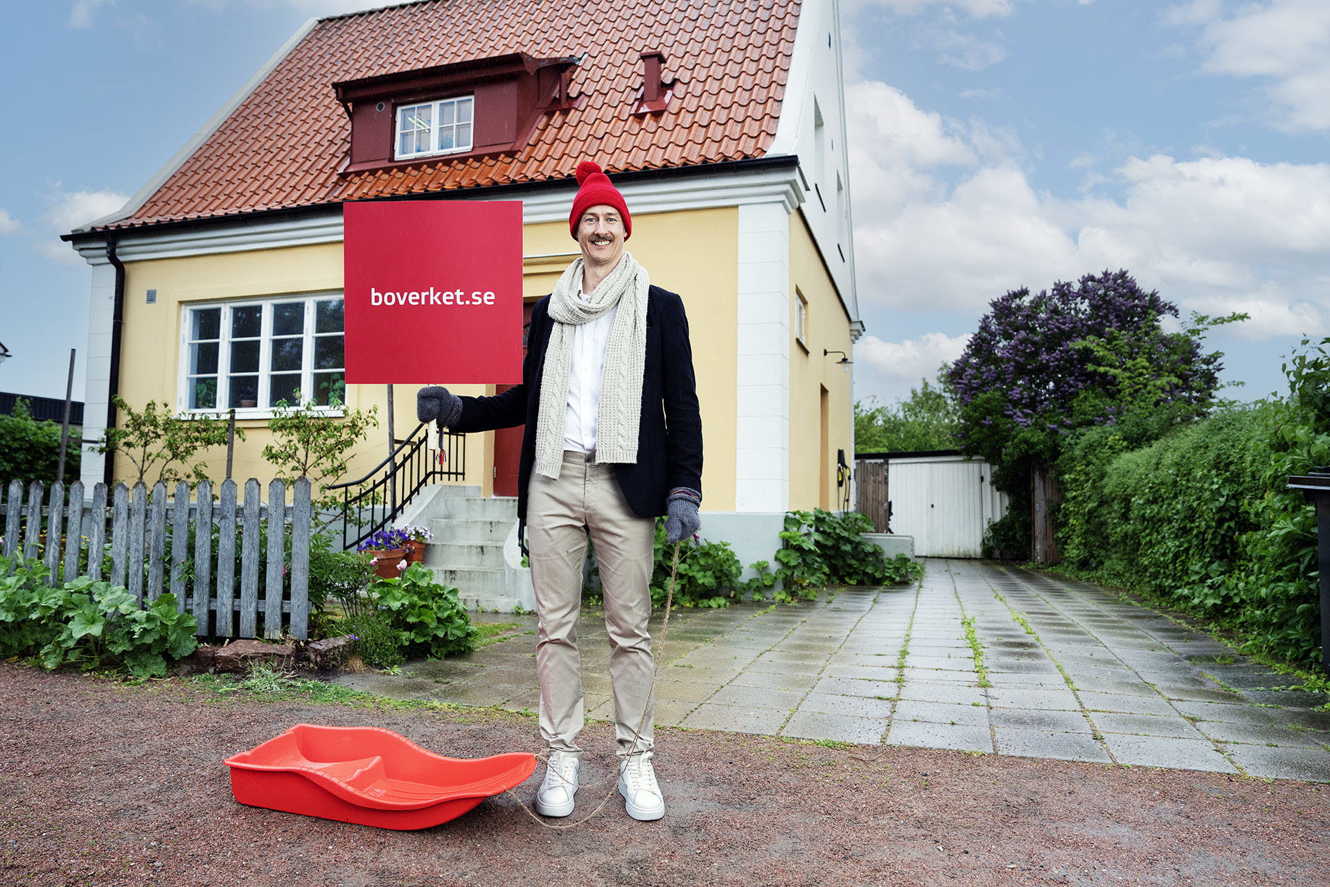 Man med pulka utanför hus